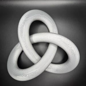 May include: A white, wooden, three-dimensional knot sculpture. The knot is made of three intertwined loops.