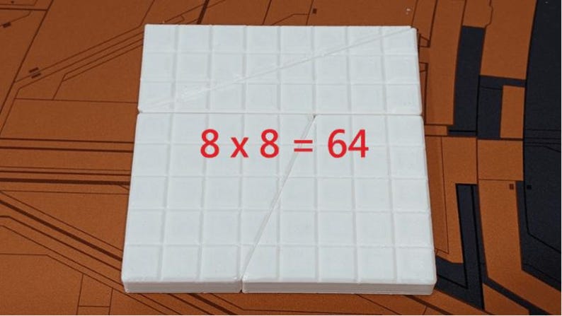 Puede incluir: Un cuadrado blanco dividido en cuadrados m&aacute;s peque&ntilde;os con una l&iacute;nea diagonal dibujada a trav&eacute;s de &eacute;l. La ecuaci&oacute;n "8 x 8 = 64" est&aacute; escrita en rojo en el cuadrado.