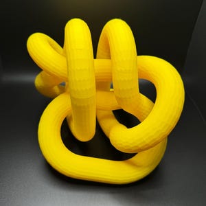 May include: A yellow 3D printed knot sculpture. The knot is made of multiple loops that are intertwined with each other.