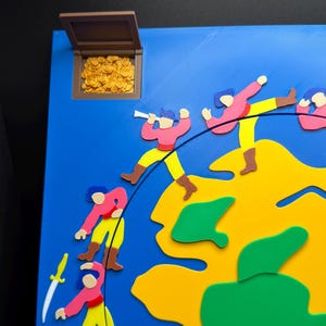 May include: A colorful, cartoonish map with a treasure chest and figures of pirates. The map features a blue background, yellow landmasses, and green islands. The figures are dressed in pink shirts, yellow pants, and brown boots. A treasure chest is open, revealing gold coins.