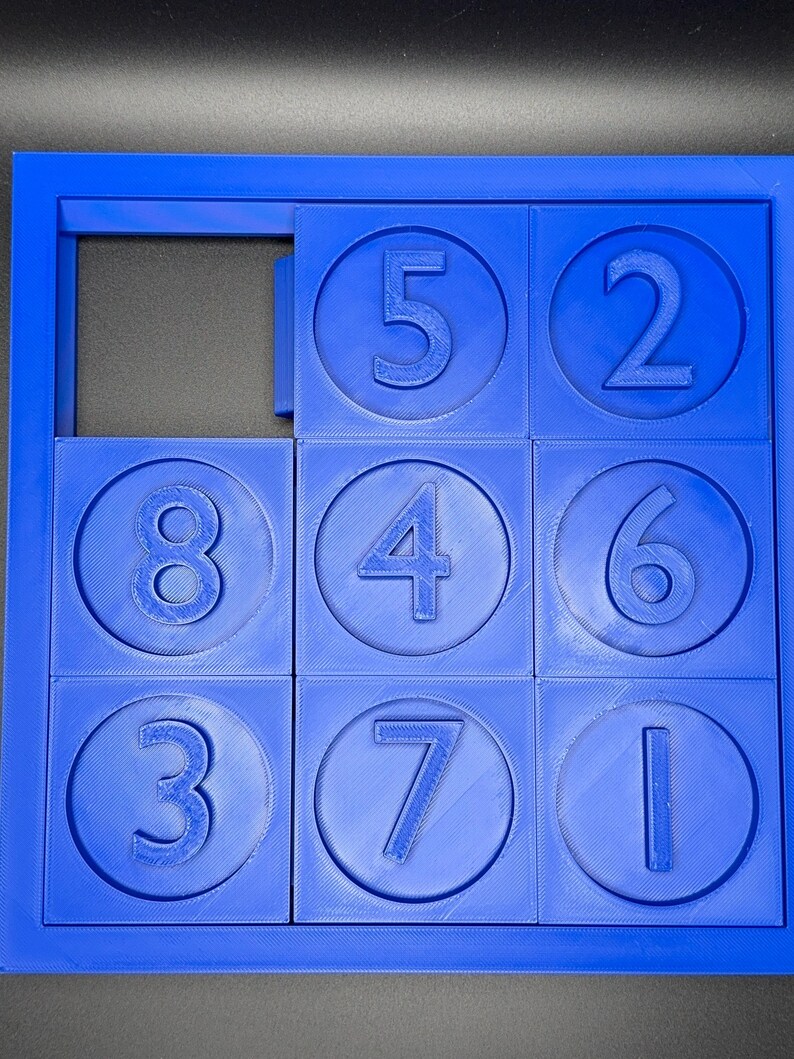 May include: A blue plastic puzzle with nine circular pieces, each containing a number from 1 to 8. The puzzle is missing one piece, leaving a blank space.