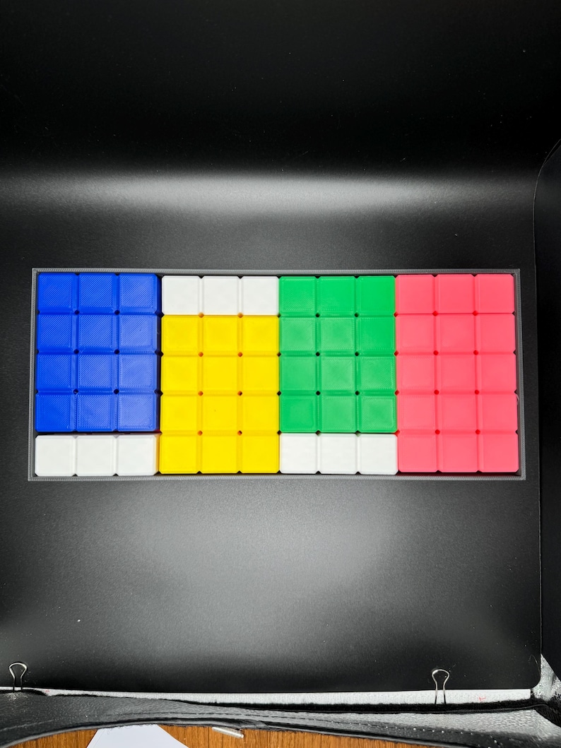 May include: A set of four 3x3 Rubik's Cube puzzles in a black case. The cubes are arranged in a row, with the colors blue, yellow, green, and pink.