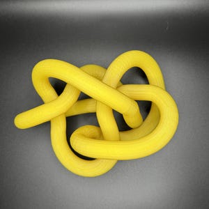 K&ouml;nnte beinhalten: Eine gelbe Knotenschnur-Skulptur. Das Seil ist dick und hat eine glatte, leicht strukturierte Oberfl&auml;che.