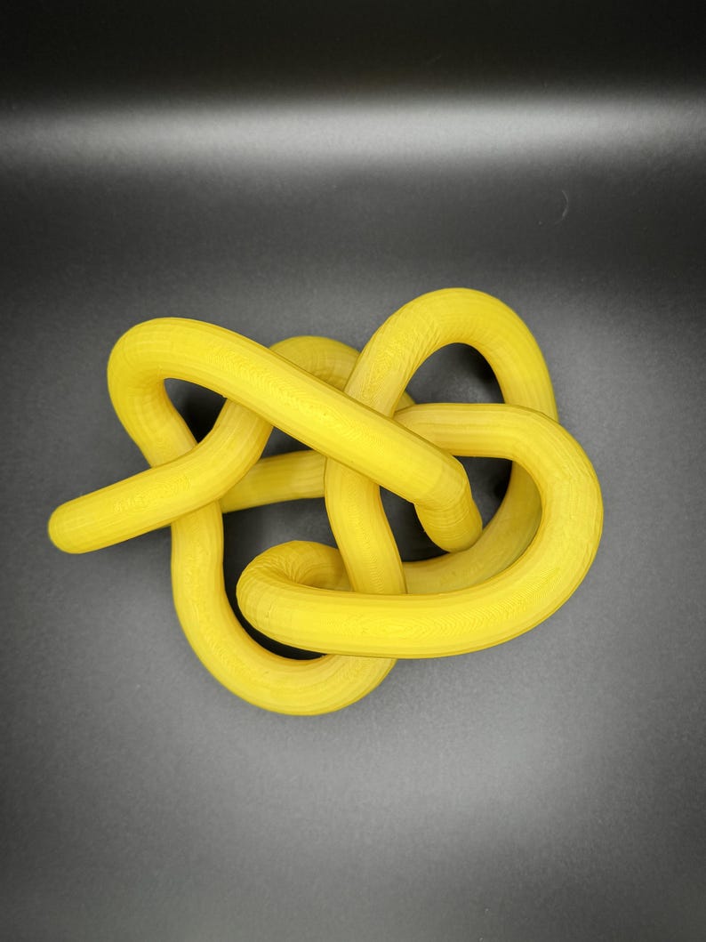 K&ouml;nnte beinhalten: Eine gelbe Knotenschnur-Skulptur. Das Seil ist dick und hat eine glatte, leicht strukturierte Oberfl&auml;che.