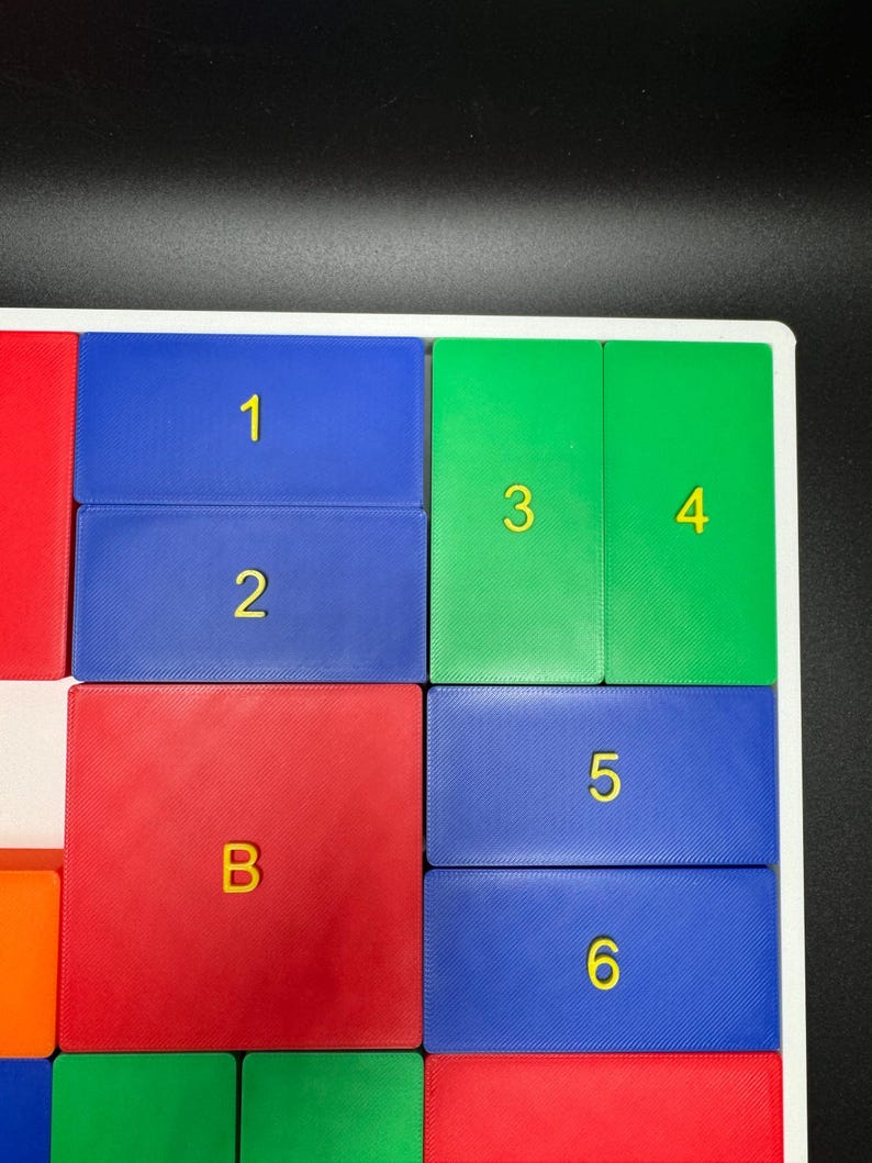May include: A colorful set of square tiles with numbers 1 through 6 and the letter B. The tiles are arranged in a grid pattern. The tiles are made of a textured plastic material.