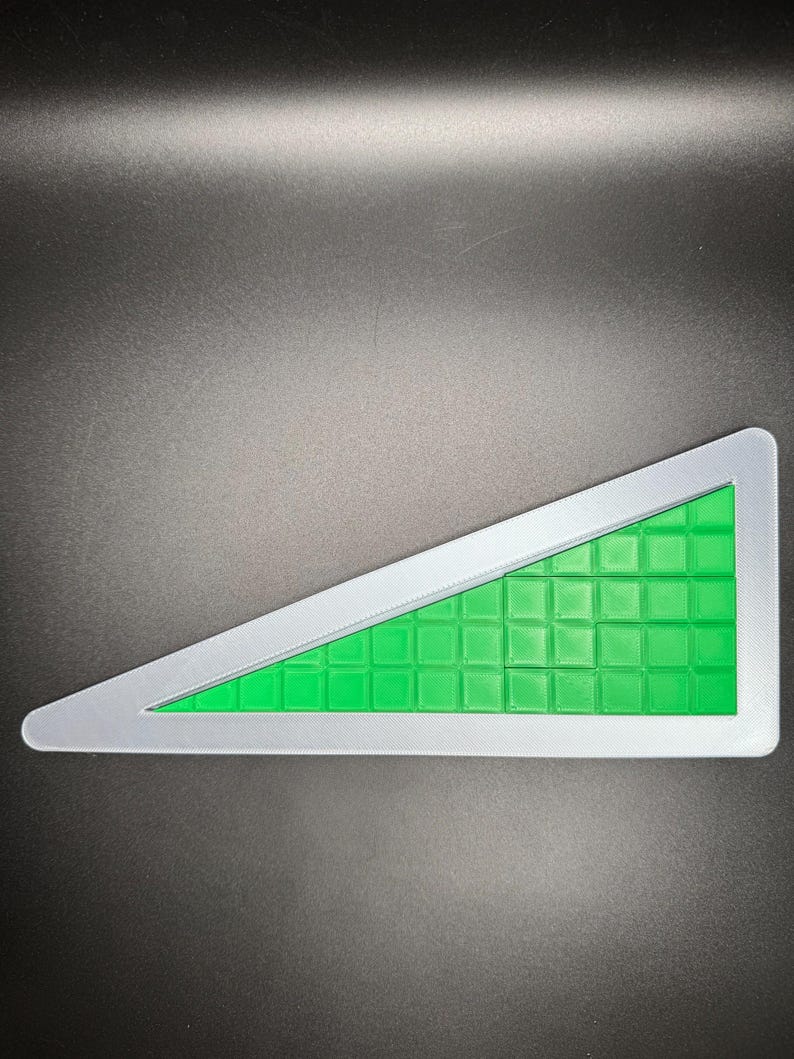 Puede incluir: Un rompecabezas triangular verde y gris con un patr&oacute;n de cuadr&iacute;cula. El rompecabezas est&aacute; hecho de peque&ntilde;os cuadrados que encajan para crear un tri&aacute;ngulo m&aacute;s grande.