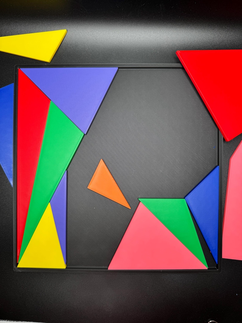May include: A colorful geometric puzzle with pieces in red, blue, green, yellow, orange, and pink. The pieces are arranged on a black background.
