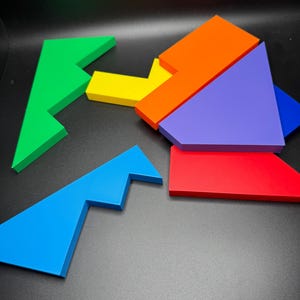 May include: A set of six colorful puzzle pieces made of wood. The pieces are shaped like different geometric shapes, including triangles, squares, and rectangles. The pieces are arranged in a random order on a black background.