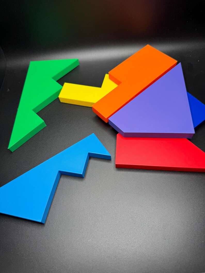 May include: A set of six colorful puzzle pieces made of wood. The pieces are shaped like different geometric shapes, including triangles, squares, and rectangles. The pieces are arranged in a random order on a black background.