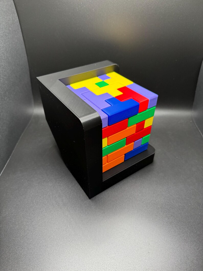 May include: A colorful block puzzle with a black base. The blocks are stacked in a tower and are arranged in a pattern. The blocks are red, orange, yellow, green, blue, and purple.
