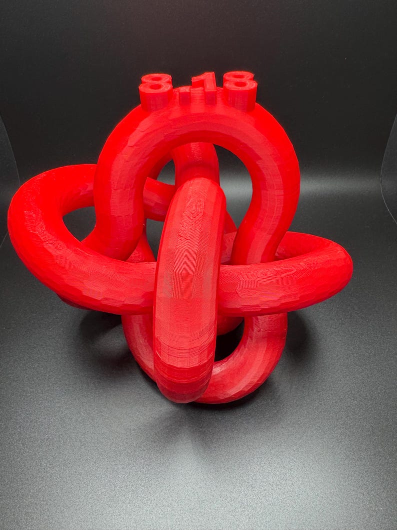 May include: A red 3D printed knot sculpture with the number "8-18" on top.
