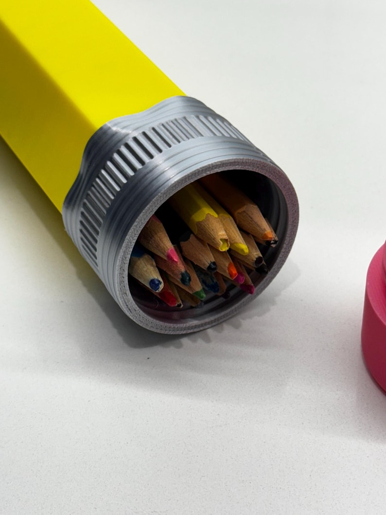 May include: A yellow pencil-shaped container with a silver lid, open to reveal a collection of colored pencils inside.