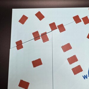 May include: A light blue and white puzzle with a pattern of small, reddish-brown wooden planks. The planks are scattered across the puzzle pieces, connected by a thin black line. The puzzle is partially assembled.