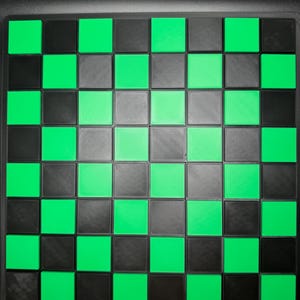 K&ouml;nnte beinhalten: Ein quadratisches Schachbrett mit schwarzem Rand. Das Brett weist ein Muster aus abwechselnd schwarzen, grauen und leuchtend gr&uuml;nen Quadraten auf. Die Quadrate sind gleich gro&szlig; und in einem Raster angeordnet, wodurch ein klassisches Schachbrettmuster entsteht.