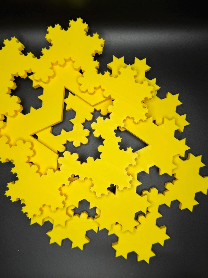 May include: A set of yellow, intricately designed, geometric shapes resembling snowflakes. The shapes are layered on top of each other, creating a visually interesting pattern.