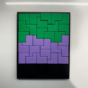 Puede incluir: Un rompecabezas con marco negro con piezas entrelazadas verdes y moradas. El rompecabezas est&aacute; formado por piezas de diferentes formas que encajan para crear un dise&ntilde;o m&aacute;s grande.