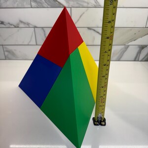 May include: A four-sided pyramid made of four different colored pieces of foam. The pyramid is red, blue, green, and yellow. The pyramid is about 7 inches tall.