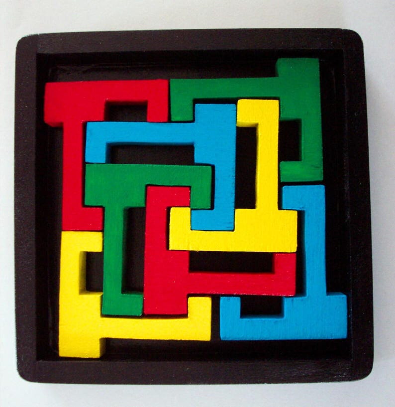 Op de afbeelding: Een houten puzzel met vier stukken in verschillende kleuren: rood, groen, blauw en geel. De stukken zijn L-vormig en passen in elkaar om een vierkant te vormen.