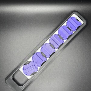 May include: A black plastic case with a handle holds eight purple guitar picks. The picks are arranged in a row and are visible through the clear plastic window.