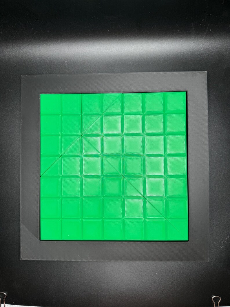 K&ouml;nnte beinhalten: Ein gr&uuml;nes quadratisches Puzzlebrett mit einem Gittermuster und diagonalen Linien. Das Brett ist aus Kunststoff und hat eine glatte Oberfl&auml;che.
