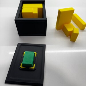 Pu&ograve; includere: Una scatola nera con un blocco verde all'interno. La scatola ha un bordo giallo. Ci sono blocchi gialli fuori dalla scatola.