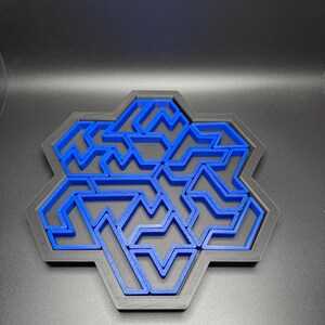 May include: A blue plastic maze puzzle in the shape of a hexagon. The maze is made up of a series of interlocking lines and curves.