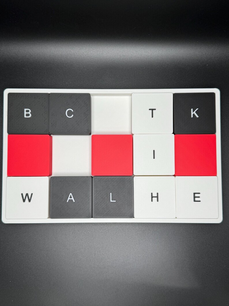 May include: A white tray with a grid of square tiles. The tiles are black, red, and white, with letters spelling "BACK THE WALL". The letters are in a bold, sans-serif font. The background is black.