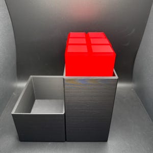May include: A black 3D printed organizer with a removable tray. The organizer has a red cube on top.