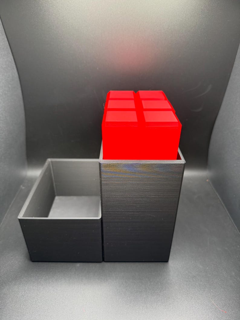 May include: A black 3D printed organizer with a removable tray. The organizer has a red cube on top.