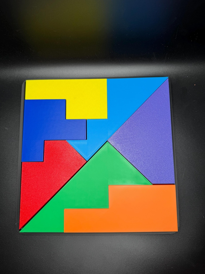 May include: A colorful wooden puzzle with seven pieces. The pieces are in the shapes of squares, rectangles, and triangles. The colors are red, blue, green, yellow, and purple.