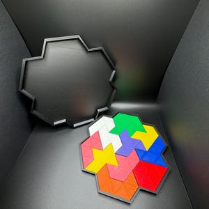 May include: A colorful geometric puzzle with six different colored pieces, including red, blue, green, yellow, pink, and white, fits together to form a hexagonal shape. The puzzle pieces are made of a textured plastic material and are arranged in a spiral pattern. The puzzle is sitting on a black surface.