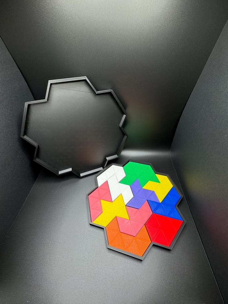 May include: A colorful geometric puzzle with six different colored pieces, including red, blue, green, yellow, pink, and white, fits together to form a hexagonal shape. The puzzle pieces are made of a textured plastic material and are arranged in a spiral pattern. The puzzle is sitting on a black surface.