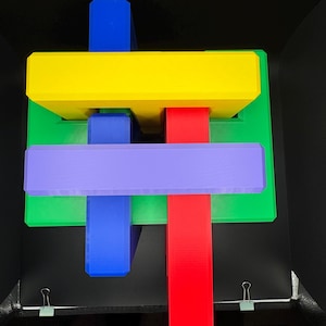 May include: A colorful wooden puzzle with four pieces. The pieces are red, yellow, blue, and purple. The puzzle is in the shape of a cross.