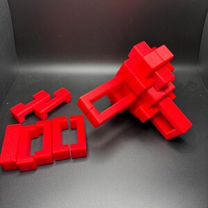 May include: A red 3D puzzle with multiple pieces that can be assembled into different shapes. The puzzle is made of plastic and is in the process of being assembled.