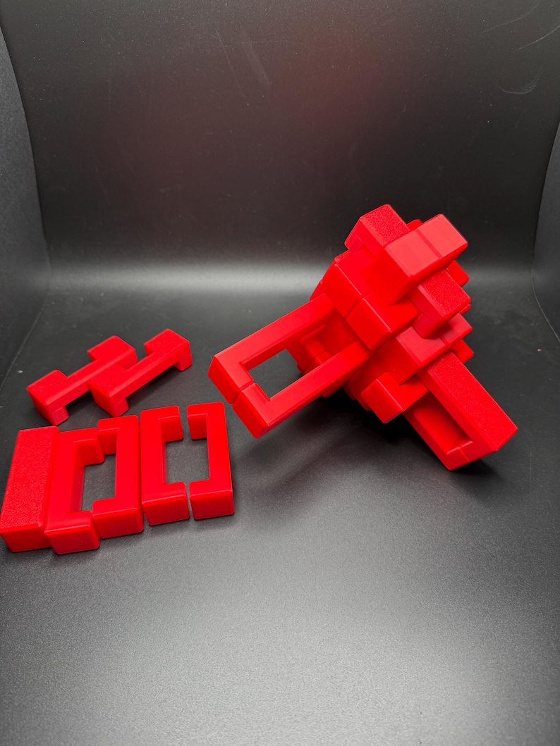 May include: A red 3D puzzle with multiple pieces that can be assembled into different shapes. The puzzle is made of plastic and is in the process of being assembled.