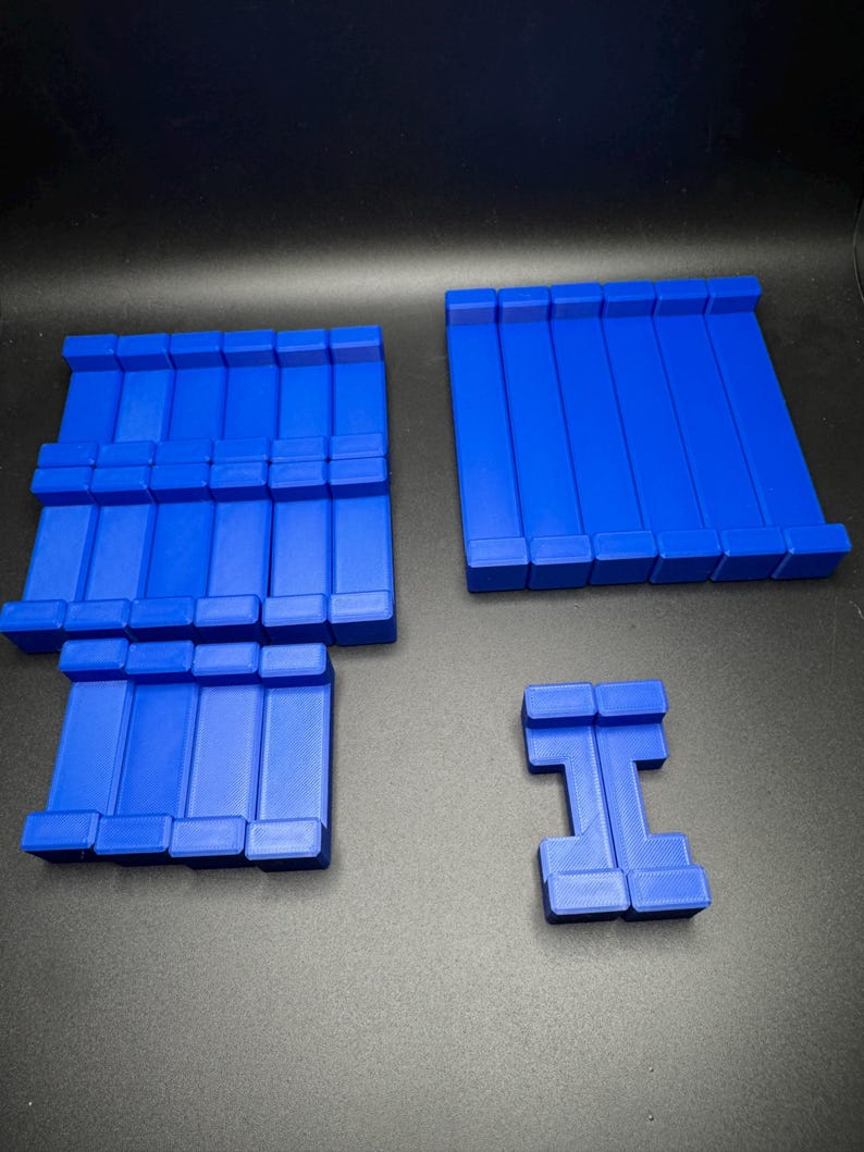 May include: A set of blue plastic building blocks. The set includes a large rectangular block, a smaller rectangular block, and a block shaped like the letter 'I'.