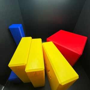 May include: Four yellow blocks with the letter 'b' on each side, stacked on top of each other. A blue block is behind the yellow blocks. A red block is on top of the yellow blocks.
