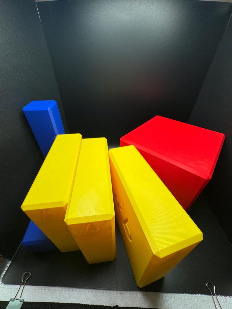 May include: Four yellow blocks with the letter 'b' on each side, stacked on top of each other. A blue block is behind the yellow blocks. A red block is on top of the yellow blocks.