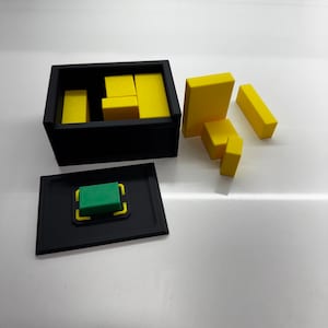 Pu&ograve; includere: Una scatola nera con un quadrato verde all'interno e blocchi gialli sparsi intorno. La scatola ha un coperchio che &egrave; aperto e i blocchi sono sparsi intorno alla scatola.