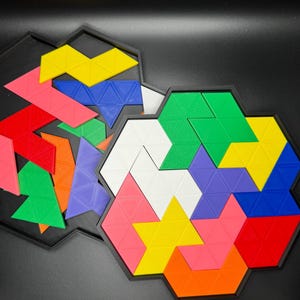 May include: A colorful geometric puzzle with triangular pieces in shades of red, orange, yellow, green, blue, purple, and white. The pieces fit together to form a star shape within a hexagonal frame.