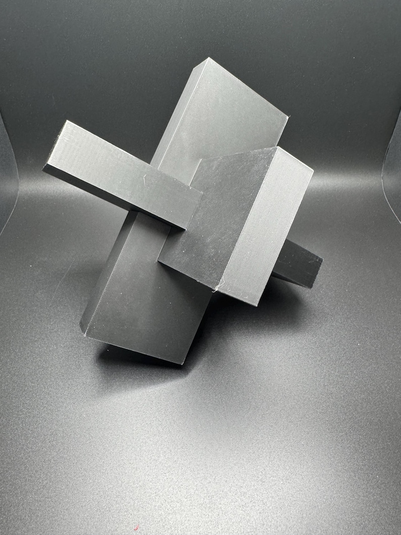 K&ouml;nnte beinhalten: Eine schwarze geometrische Skulptur aus drei sich schneidenden rechteckigen Formen.