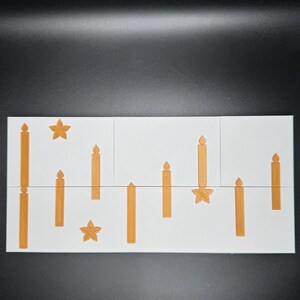 Puede incluir: Una baldosa rectangular blanca con un patr&oacute;n repetido de velas y estrellas doradas. Las velas var&iacute;an en altura y dise&ntilde;o, creando un tema festivo y decorativo. La baldosa est&aacute; dividida en tres secciones.