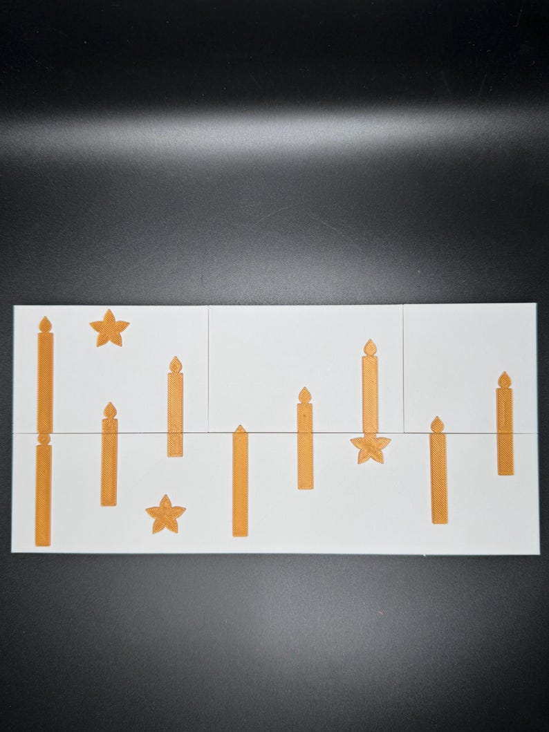 Puede incluir: Una baldosa rectangular blanca con un patr&oacute;n repetido de velas y estrellas doradas. Las velas var&iacute;an en altura y dise&ntilde;o, creando un tema festivo y decorativo. La baldosa est&aacute; dividida en tres secciones.