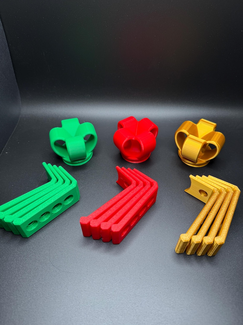 May include: Three sets of 3D printed plastic pieces in green, red, and gold. Each set includes a crown-shaped piece and five curved pieces.
