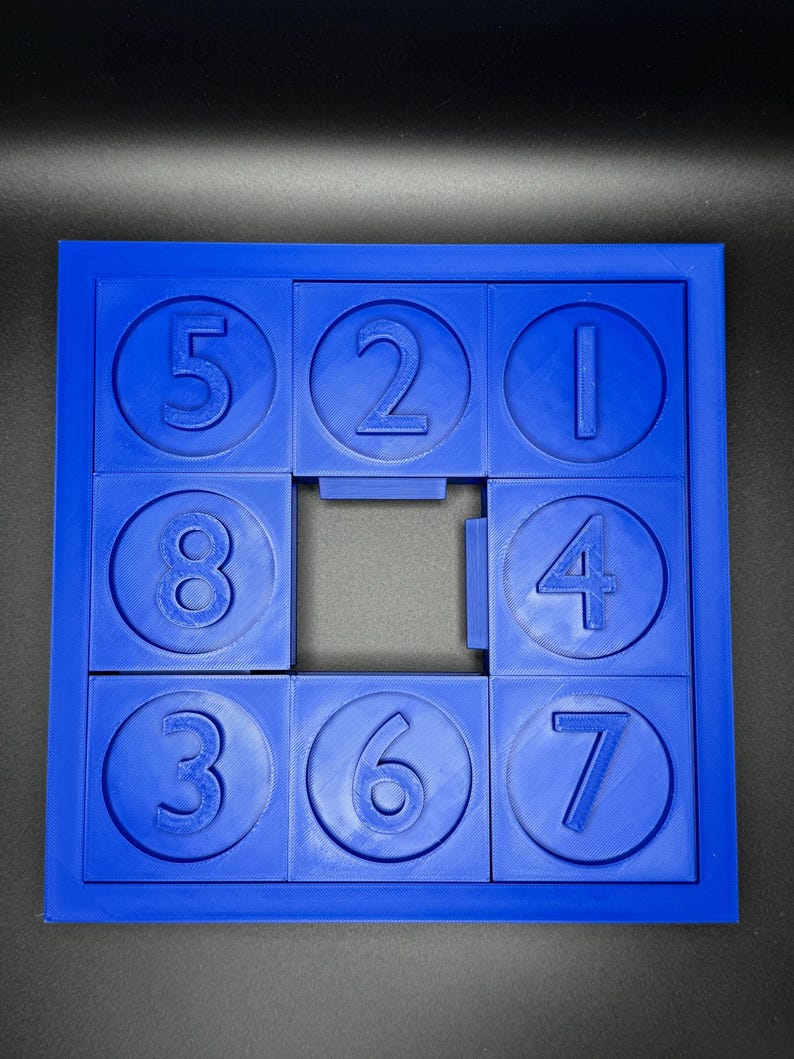 May include: A blue plastic puzzle with nine circular pieces, each with a number from 1 to 8. The puzzle is missing the number 9 piece.