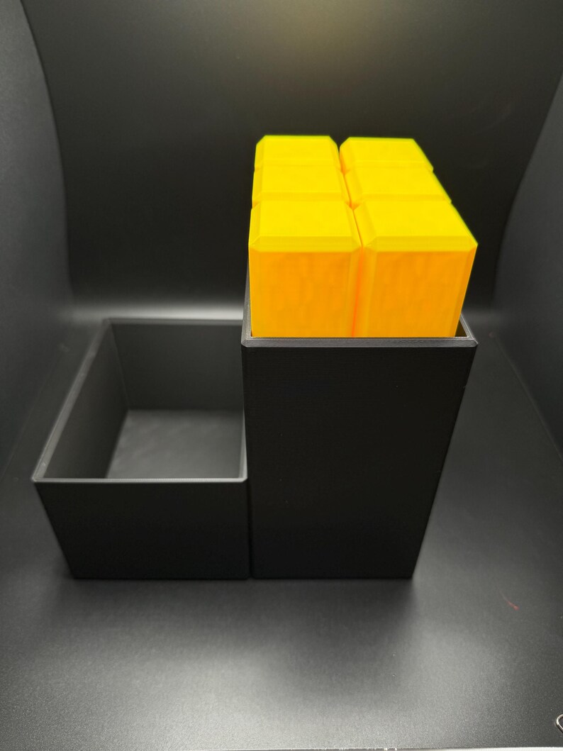 May include: A black organizer with a removable tray and a stack of bright yellow cubes. The organizer is made of plastic and has a modern design.