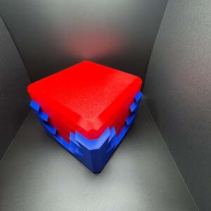 May include: A red and blue box with a geometric design. The box is closed and has a smooth, glossy finish.