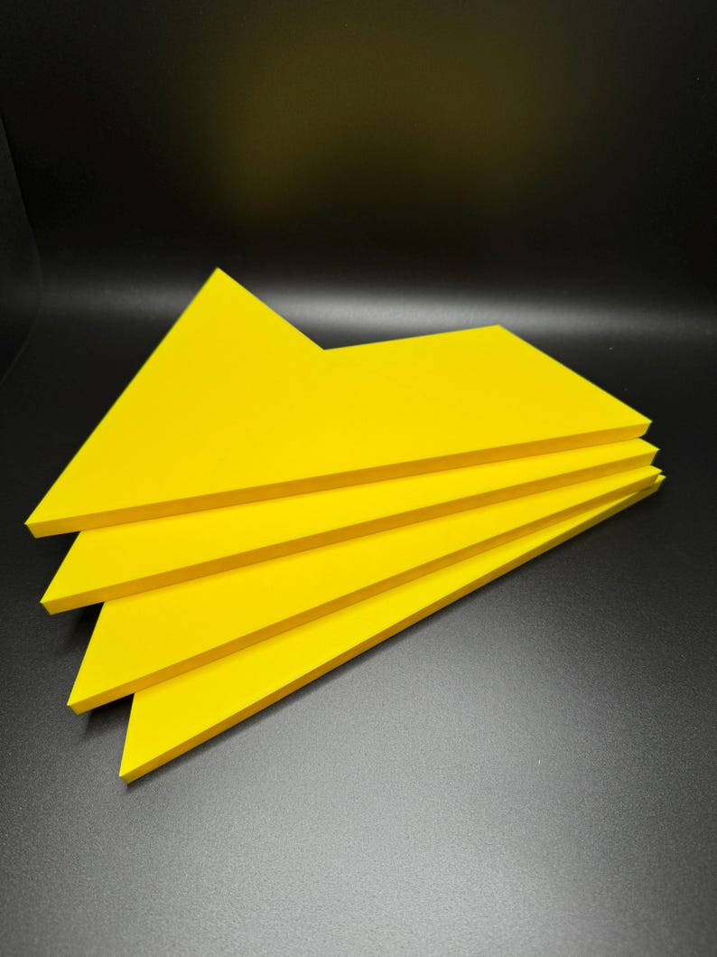 May include: A stack of four bright yellow triangular shaped pieces of paper.