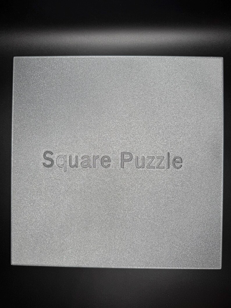 May include: A silver square puzzle with the text "Square Puzzle" printed on the front.