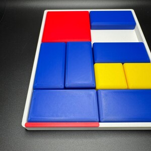 Op de afbeelding: Een witte dienblad met een rood, blauw en geel geometrisch patroon. Het dienblad is gemaakt van plastic en heeft een textuur.